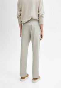 Lichtgrijze broek met een rechte pijp design, gemaakt van zacht materiaal. Beschikt over twee achterzakken en een gladde tailleband.