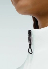 White high-collared garment featuring a black zipper with a loop pull, smooth texture, and a close-up view of the neckline area.