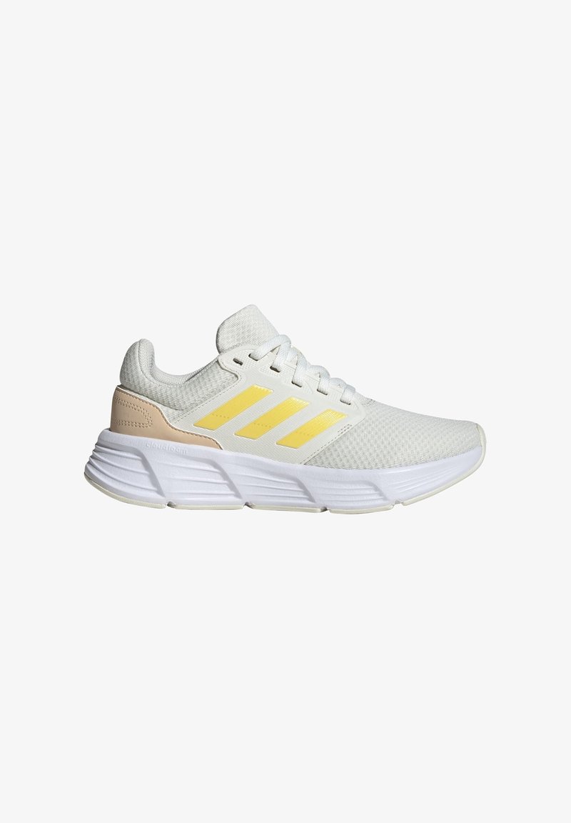 Scarpa sportiva bianca con strisce gialle e accenti beige chiaro, realizzata in tessuto texturizzato con collo imbottito e suola ammortizzata.