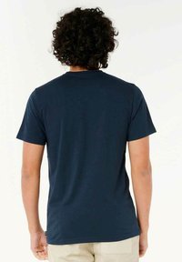 Marineblå T-shirt med kortærmer og rund hals. Glat bomuldsstof. Minimale sømme med et lille mærke ved den nederste søm.