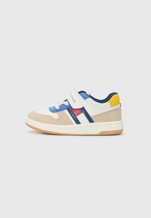 Dziecięce trampki typu low-top w blokach kolorów beżowego, białego, niebieskiego, czerwonego i żółtego, z niebieską wyściółką i białym zapięciem na rzep.