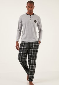Un top de pijama gri cu mânecă lungă, cu decolteu rotund și guler în carouri alb-negru, asortat cu pantaloni în carouri alb-negru.