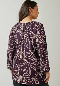 Lilla langærmet top med et lyst beige bladmønster, afslappet pasform og rynket halsudskæring. Blød tekstur og let draperet stil.