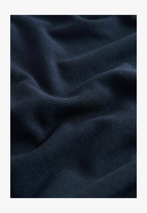 Tessuto blu navy scuro con trama testurizzata, caratterizzato da pieghe e drappeggi morbidi, che evidenziano la sua superficie liscia e soffice.