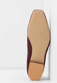 Semelle d'une chaussure en daim bordeaux avec un bout carré, semelle brun clair avec des sections texturées et taille 37 imprimée près du talon.