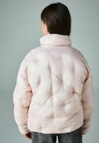 Lichtroze gewatteerde jas met een textuurafwerking, uitgerust met een hoge kraag en doorgestikte details. Merklabel aan de achterkant van de kraag.