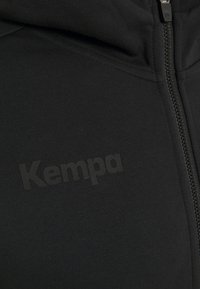 Sort zip-up hoodie med tekstureret stof, fremtrædende "Kempa" logo i en diskret mat finish og hætte med snørre.