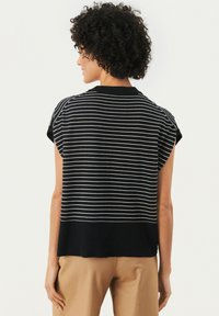 Suéter de manga corta a rayas en blanco y negro con cuello acanalado, que presenta un corte relajado y un dobladillo inferior sólido en negro.