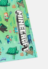 Πράσινα μαγιό εμπνευσμένα από το Minecraft με ψηφιακά αποδομημένα θαλάσσια πλάσματα και χαρακτήρες, με έντονο λογότυπο "Minecraft" σε μαύρο χρώμα.