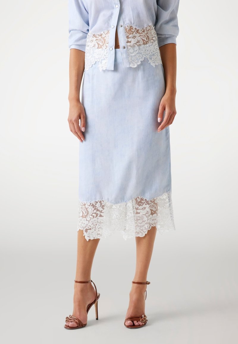 Fustă din in bleu deschis, cu un tiv din dantelă albă, având o siluetă ajustată și modele florale delicate. Potrivită cu sandale cu toc maro.