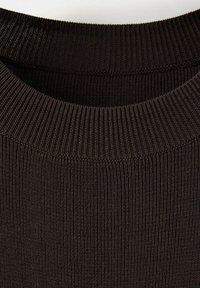 Gros plan d'un col rond en maille côtelée marron foncé sur un pull, montrant la texture du tissu et les détails des coutures.