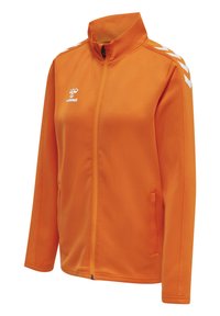 Orange zip-up jakke lavet af glat stof, med høj krave, sidelommer og hvide chevron-detaljer på skuldrene.