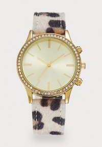 Goldene Uhr mit mit Kristallen besetzter Lünette, minimalistischen goldenen Ziffern und einem strukturierten Tiermusterarmband in Beige-, Schwarz- und Brauntönen.