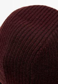 Close-up of a dark brown knitted fabric with vertical ribbed pattern, showing soft, textured yarn fibers.