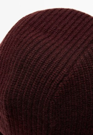 Close-up of a dark brown knitted fabric with vertical ribbed pattern, showing soft, textured yarn fibers.