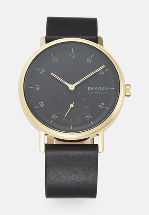 Montre-bracelet analogique avec boîtier doré, cadran noir affichant l'heure 10h10, bracelet en cuir noir et petit cadran des secondes à 6 heures.
