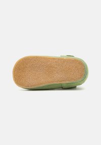 Grüner Wildlederschuh mit einer strukturierten braunen Sohle. Verfügt über ein weiches Futter und einen einfachen verstellbaren Riemen. Flaches Design, runde Zehenform.