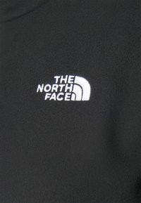 Černý fleecový svetr s bílým vyšitým logem "The North Face" s designem půloblouku na levé straně.