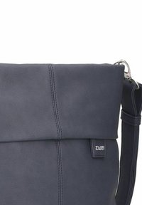 Borsa in pelle blu navy con pattina pieghevole, caratterizzata da dettagli di cucitura sottili e un accento in metallo laterale. Include una tracolla regolabile.