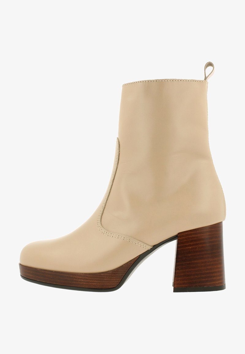 Beige enkellaarsje met een gladde afwerking, een afgeronde neus, elastische zijpanelen en een blokhak van hout. Minimale naden en geen zichtbare hardware.