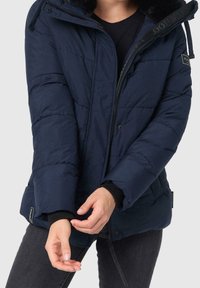 Granatowa kurtka puchowa z odpinanym kapturem wyłożonym futrem, zamek z przodu, elastyczne mankiety i kieszenie po bokach; pikowana faktura materiału.