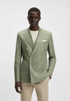 Giacca doppiopetto in tessuto verde chiaro con finitura testurizzata. Presenta due tasche frontali e bottoni color crema. Include un fazzoletto da taschino bianco.