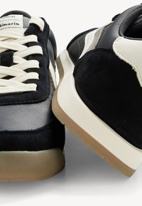 Schwarze Wildleder- und Mesh-Sneaker mit cremfarbenen Schnürsenkeln und Akzenten. Verfügt über eine erhöhte Ferse und eine strukturierte Gummisohle. Klassisches athletisches Design.
