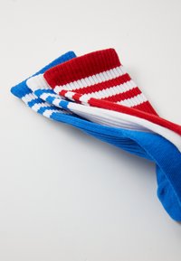 Drie paar sokken: één effen blauw, één gestreept rood en wit, en één blauw met witte strepen, met ribbels aan de manchetten en een zachte textuur.