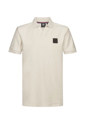 Kortærmet poloshirt i cremefarvet bomuld med en tekstureret finish. Har en V-udskæring og en sort firkantet logopatch på brystet.