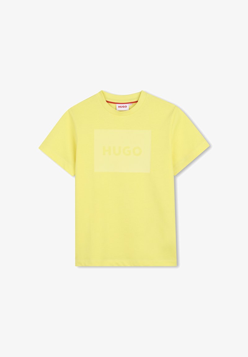T-shirt jaune à manches courtes et col rond, avec un logo "HUGO" discret imprimé à l'intérieur d'un rectangle jaune légèrement plus clair sur la poitrine.