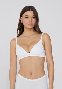 Sujeción inalámbrica blanca con tirantes finos, escote en V y diseño sin costuras. Tela suave y lisa con un acabado mate.