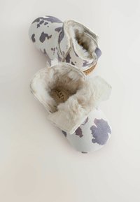Scarpine per neonati marroni e crema con design a macchie di mucca. Fodera in morbido peluche, suole robuste e chiusura regolabile con velcro.