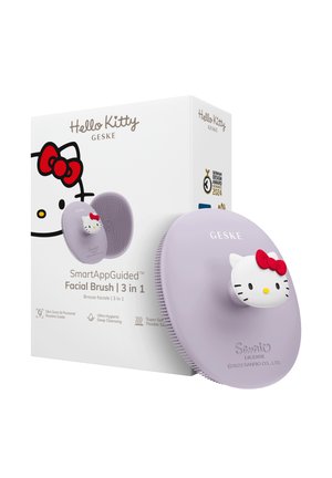 Brosse faciale ovale SmartAppGuided lavande avec poignée en forme de visage Hello Kitty à côté d'une boîte blanche présentant un design Hello Kitty et les détails du produit.