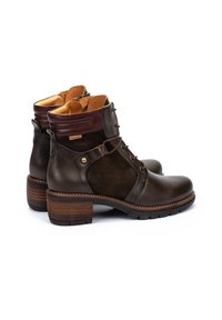 Botas de tobillo de cuero marrón y ante con tacón apilado, parte frontal con cordones y costuras en contraste. Presentan un acento de hardware lateral.