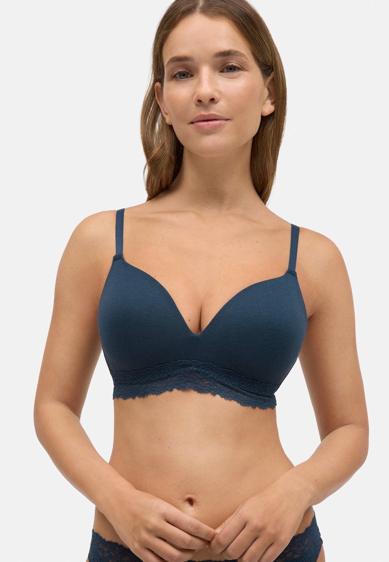 Sostén azul de canalé con bordes de encaje, que presenta una forma de escote en V profundo y tirantes ajustables. Textura de tela suave y acentos de encaje floral.