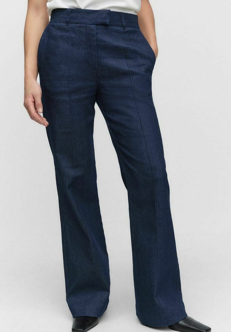 Ciemnoniebieskie spodnie dżinsowe o prostych nogawkach, z przednimi kieszeniami i gładką fakturą. Talia wyposażona w szlufki na pasek.