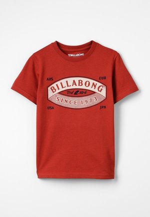 Rød Billabong T-shirt med korte ærmer med logo og tekst "Since 1973" samt landforkortelserne AUS, EUR, USA, JPN på forsiden.