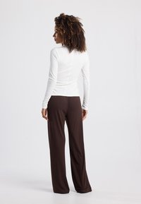 Long-sleeve white top and brown wide-leg pants, both made of soft fabric. The top features a fitted design, while the pants have a loose cut.