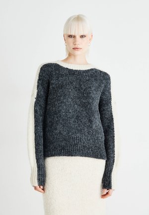 Knit sweater with a heather gray body, cream-colored sleeves, ribbed texture, and a round neckline. Designed with a relaxed fit.