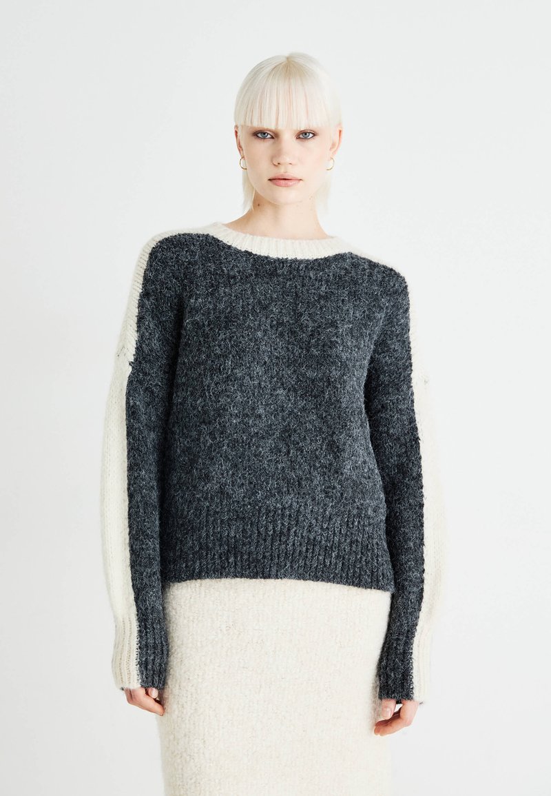 Maglione lavorato a maglia con corpo grigio heather, maniche color crema, texture a coste e scollatura rotonda. Progettato con una vestibilità morbida.