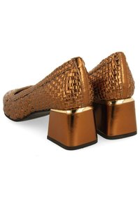 Ballerines en cuir tressé bronze avec talons carrés et accents métalliques ; surface texturée avec une couleur cohérente et un design épuré.