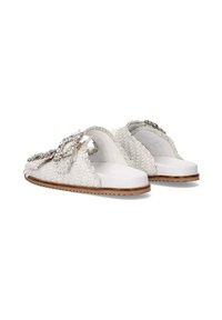 Las sandalias deslizantes tejidas en blanco presentan un empeine texturizado con un adorno decorativo plateado. La suela plana tiene una suela de goma marrón.