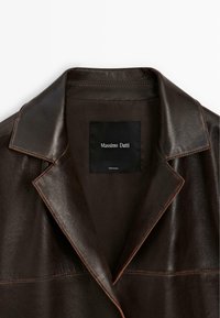 Mørkebrunt læderjakke krave og slag med synlig syning og en sort label med teksten "Massimo Dutti" på det indvendige for.