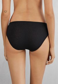 Czarne, żeńskie bikini o wysokim stanem, z prążkowanym wzorem i bezszwami brzegami, o gładkiej fakturze. Podkreśla naturalny kształt.