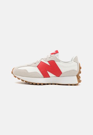 Biało-szary sneaker z dużym czerwonym "N" po boku, gumową podeszwą z ćwiekami i czerwoną metką na języku.