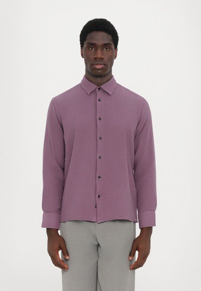 Purple long-sleeve button-up shirt with a collar, featuring black buttons and a slightly textured fabric. Paired with light gray pants.