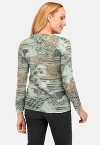 Langearmshirt in een veelkleurig abstract patroon met groene, bruine en crèmekleuren. Lichtgewicht, aansluitend ontwerp met ribbeltextuur.