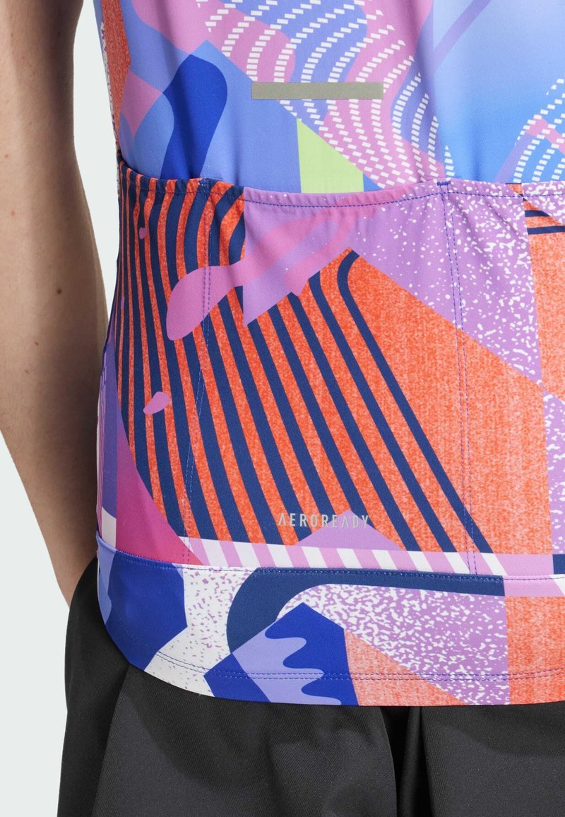 Top deportivo multicolor con patrones abstractos en rosa, azul, naranja y púrpura. El material tiene una textura suave con elementos de diseño divertidos.