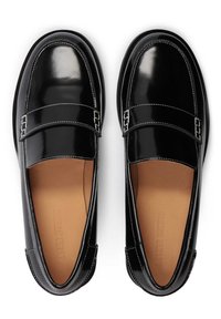 Mocassins en cuir verni noir avec un bout arrondi, deux boucles, et des surpiqûres blanches contrastantes ; semelle intérieure en cuir fauve visible.