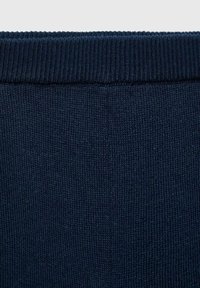 Mörkblått stickat tyg med en ribbad textur längst upp. Materialet är mjukt och elastiskt, lämpligt för avslappnad klädsel.